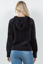 Woman wearing a black ultra-soft hoodie with a drawstring hood.