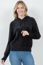Woman wearing a black ultra-soft hoodie with a drawstring hood.