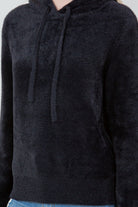 Woman wearing a black ultra-soft hoodie with a drawstring hood.