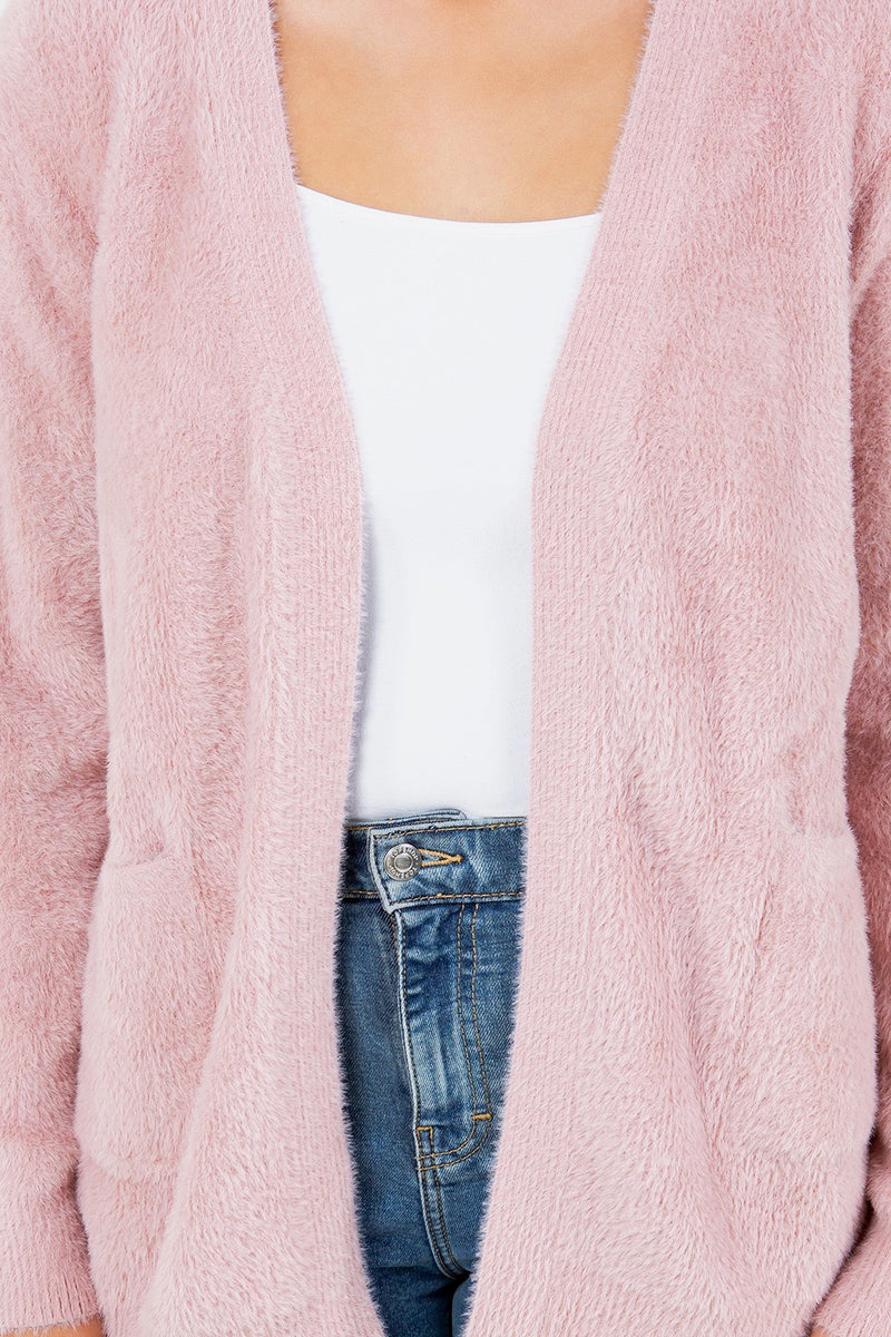Woman wearing a soft pink open-front cardigan with pockets.