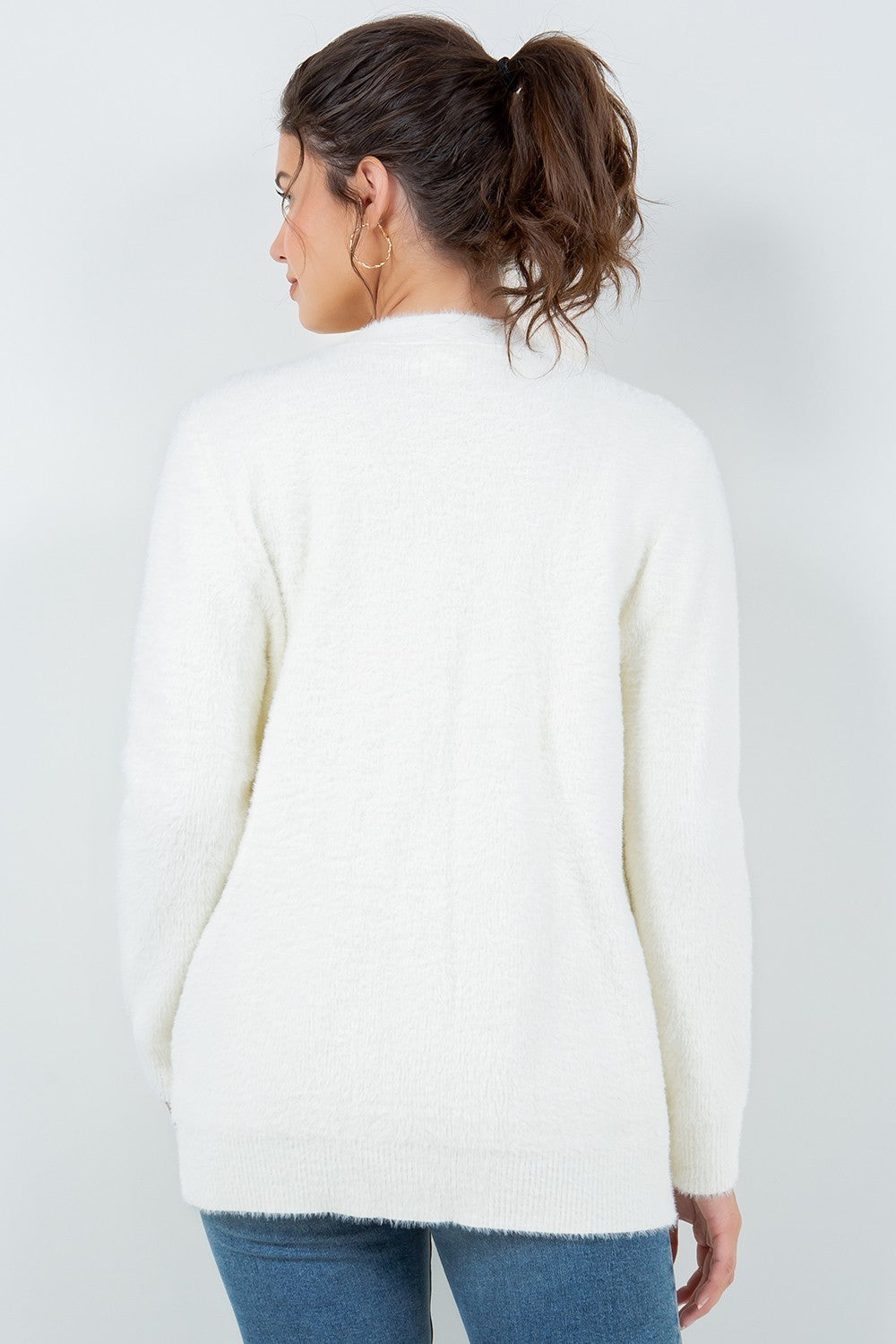 Woman wearing a soft white open-front cardigan with pockets.