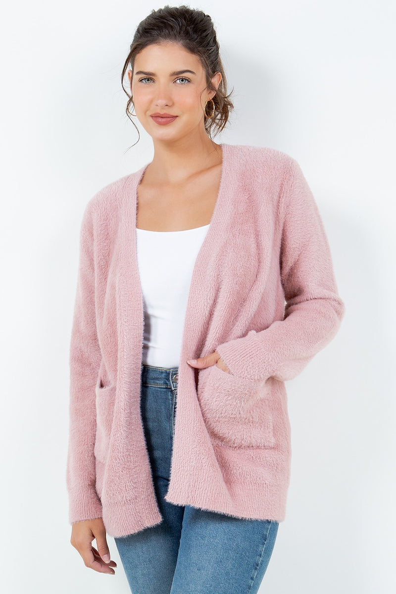 Woman wearing a soft pink open-front cardigan with pockets.