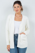 Woman wearing a soft white open-front cardigan with pockets.