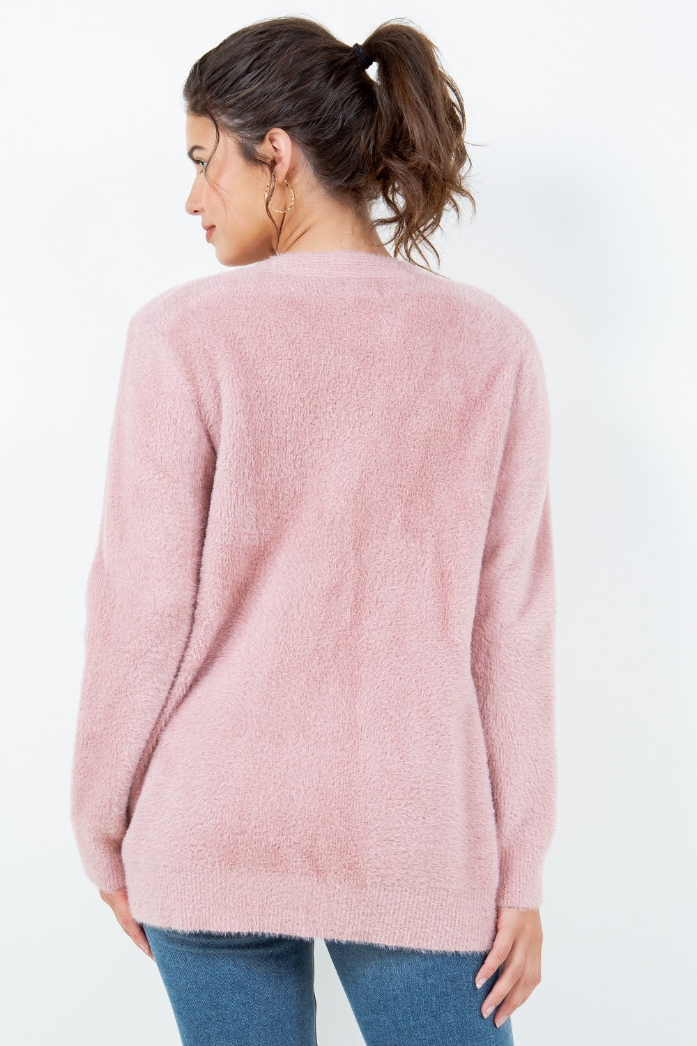 Woman wearing a soft pink open-front cardigan with pockets.