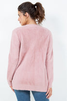 Woman wearing a soft pink open-front cardigan with pockets.