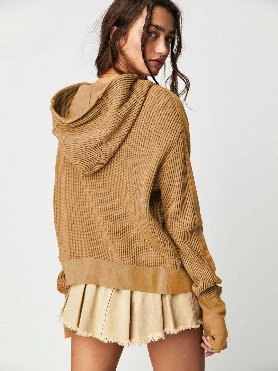 Woman wearing a Sahara Sky Hooded Jacket with a zip-up front, textured waffle knit, and button detailing in blue and brown tones.