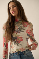 Model wearing a fitted sheer mesh long sleeve top with red, pink, and green floral print, paired with blue jeans.