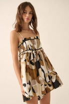 Woman wearing an abstract printed romper in warm earth tones with a smocked bodice and flowy shorts.