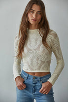 Model wearing the Celestine Lace Top in cream and black lace with long sleeves and floral mesh pattern