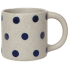 White mug with blue polka dots on a white background