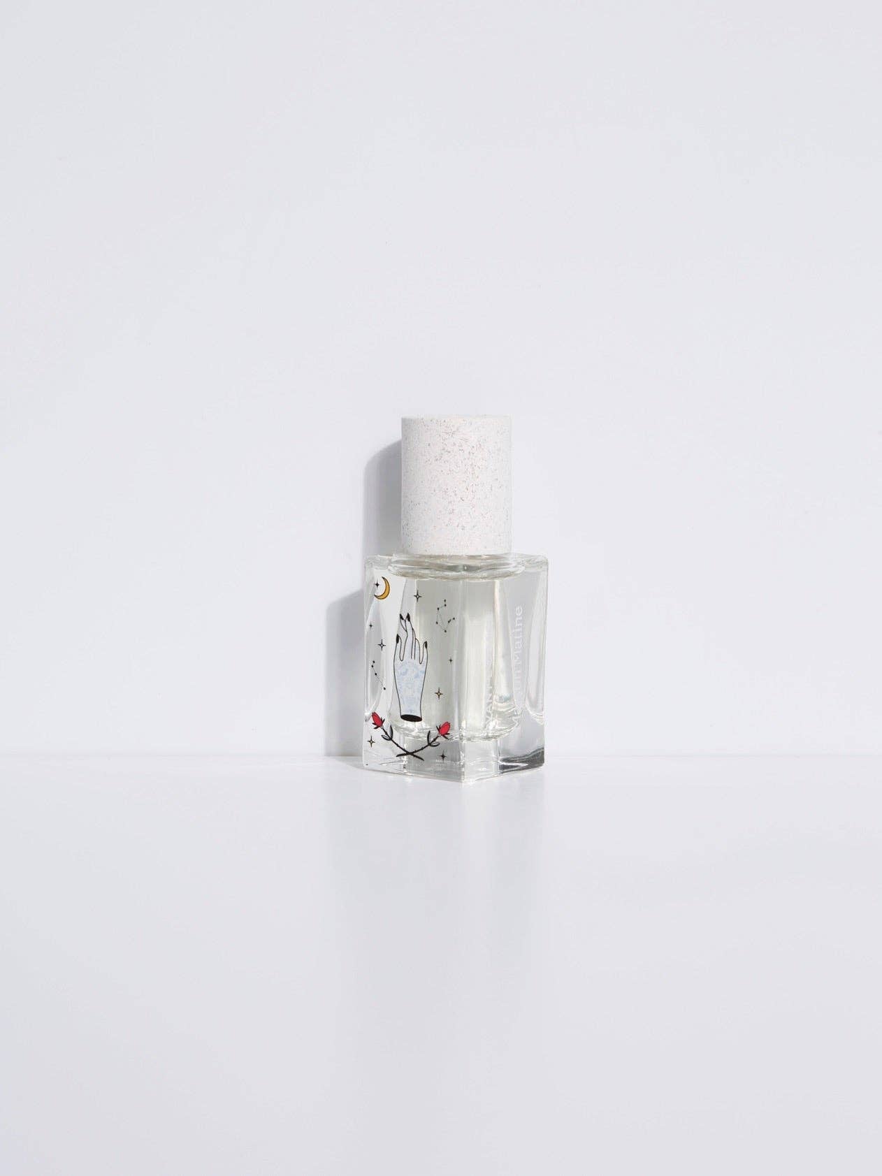 Maison Matine Avant l’Orage perfume bottle with celestial illustrations, placed among citrus fruits and sample vials on blue fabric