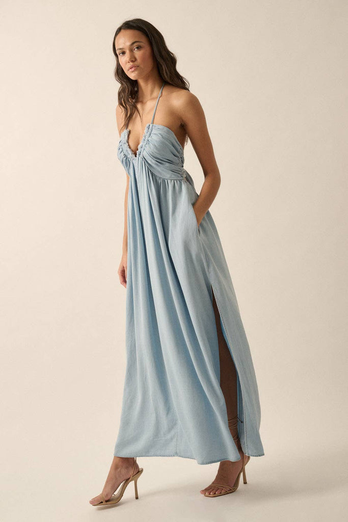 Woman wearing a light blue halter maxi dress with a plunging neckline, side slit, and flowy fit.