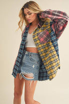 Woman wearing an oversized plaid colorblock flannel shirt in pink, yellow, and navy tones with raw hems.