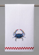 A white waffle weave kitchen towel with an embroidered blue crab design and red checkered trim.