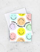 Colorful greeting card with pastel smiley and frowny faces and the text "Have a Happy Birthday" in black.