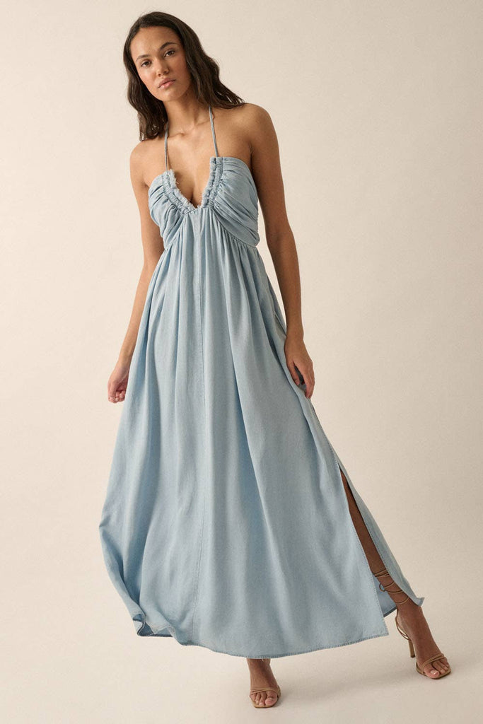 Woman wearing a light blue halter maxi dress with a plunging neckline, side slit, and flowy fit.