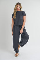 Woman wearing pleated bottom knitted pants in relaxed fit with drawstring waist and ankle detail.