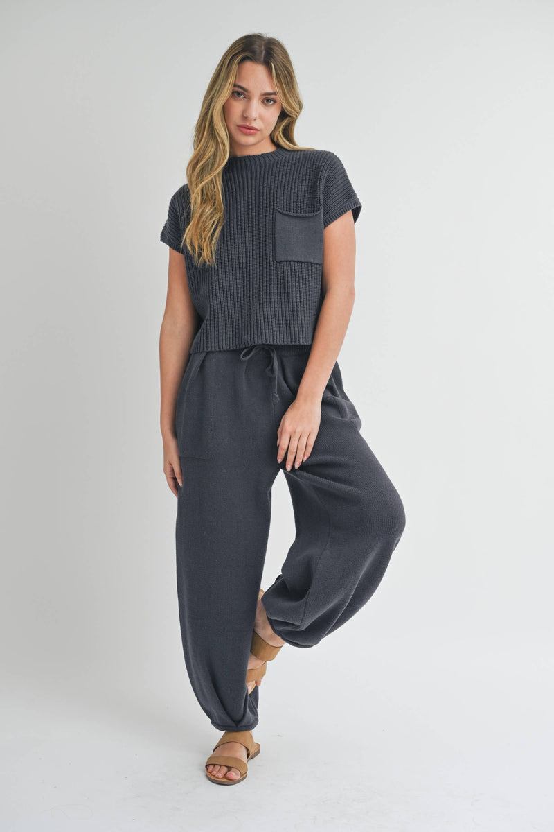 Woman wearing pleated bottom knitted pants in relaxed fit with drawstring waist and ankle detail.