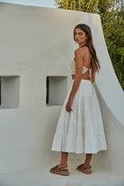 Model wearing a crochet halter crop top in black and cream, styled with jeans and a skirt, showing detailed open-stitch design.