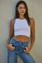 Woman wearing a fitted waffle-texture cropped tank top in green and white, styled with casual denim and neutral pants.