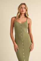 Woman wearing a sage green ribbed midi dress with spaghetti straps and front button detailing.
