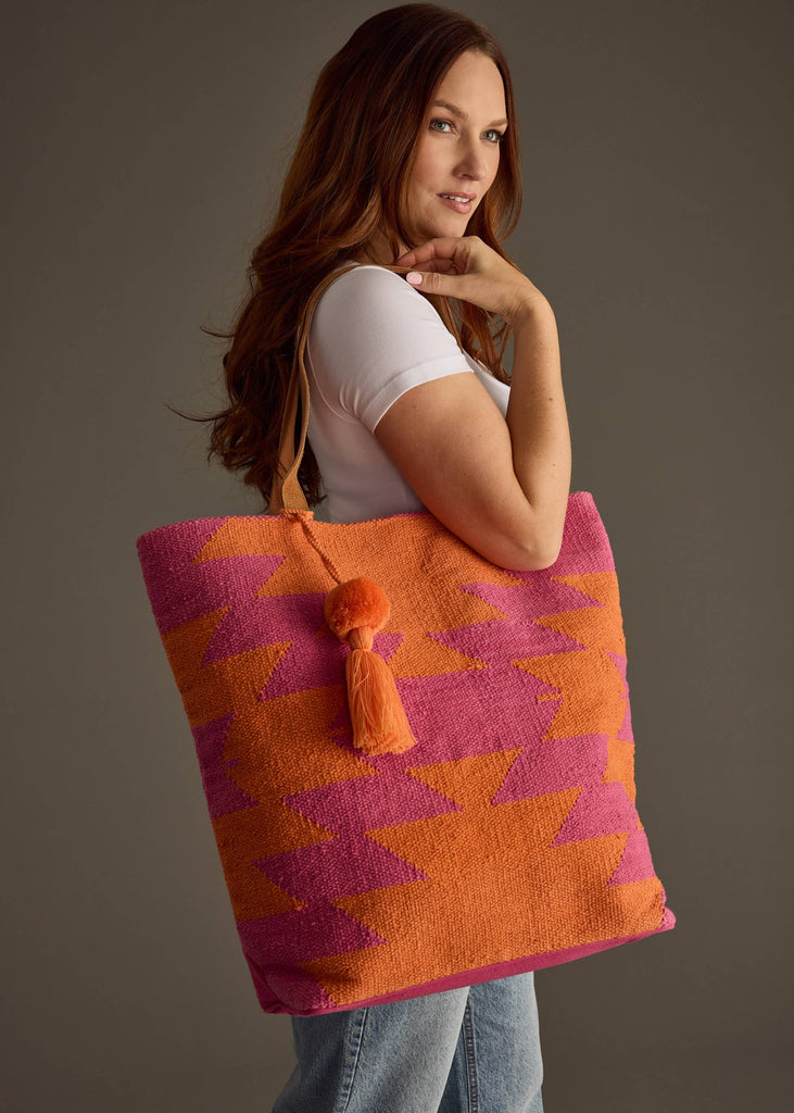 Bright pink and orange zigzag patterned tote bag with tassel charm and leather straps