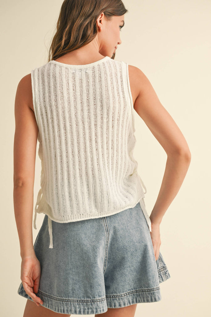 White open-knit tank top with side-tie details, styled with denim skort and jeans.