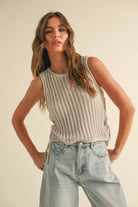 Woman wearing a striped sleeveless top and light blue jeans against a plain background
