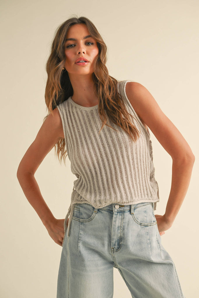 Woman wearing a striped sleeveless top and light blue jeans against a plain background