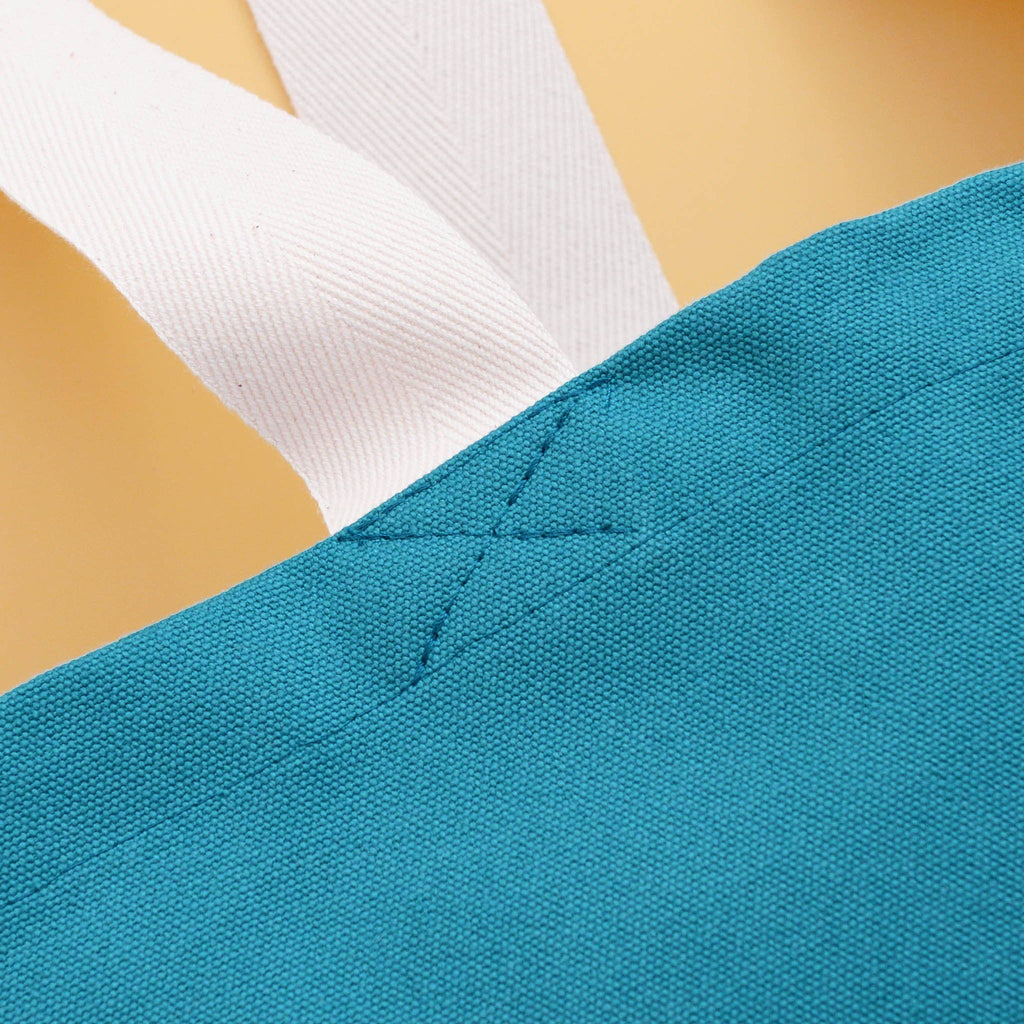 Teal tote bag with “Sunshine Appreciation Society” in white text, held by a person in a green dress at the beach