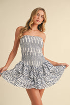 Strapless smocked mini dress with open back, blue and white pattern, and layered ruffle skirt