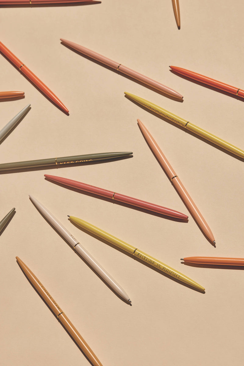"Positivity" slim metal pen set of four in assorted bright colors, each featuring an inspirational message, packaged in a mint green box.