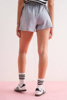 Close-up of a woman wearing gray elastic waist shorts with side zipper details.
