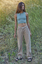 Woman wearing a fitted waffle-texture cropped tank top in green and white, styled with casual denim and neutral pants.