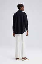Model wearing black oversized shirt with cream embroidery on shoulders and front yoke.