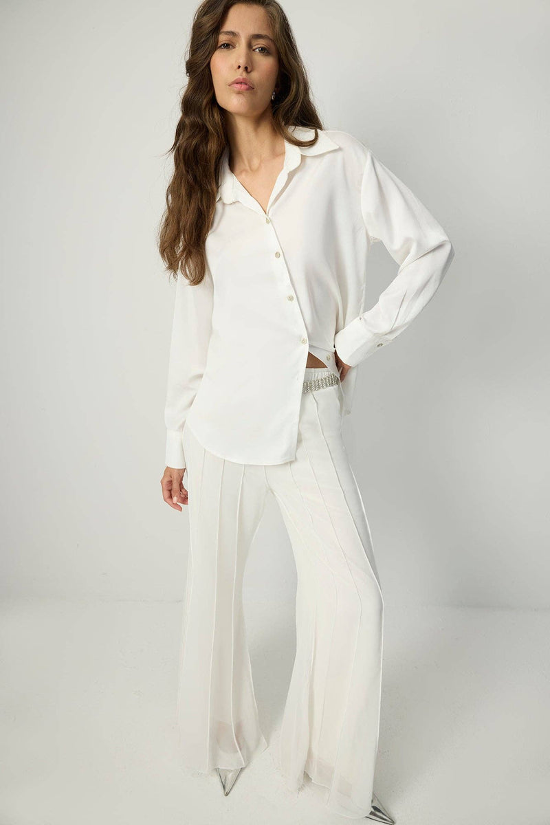 White pleated chiffon flared trousers with high waist and flowy wide legs.