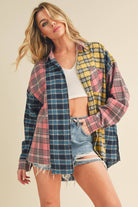 Woman wearing an oversized plaid colorblock flannel shirt in pink, yellow, and navy tones with raw hems.