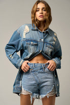 Close-up of asymmetrical distressed denim shorts with frayed hem and high-waisted fit.