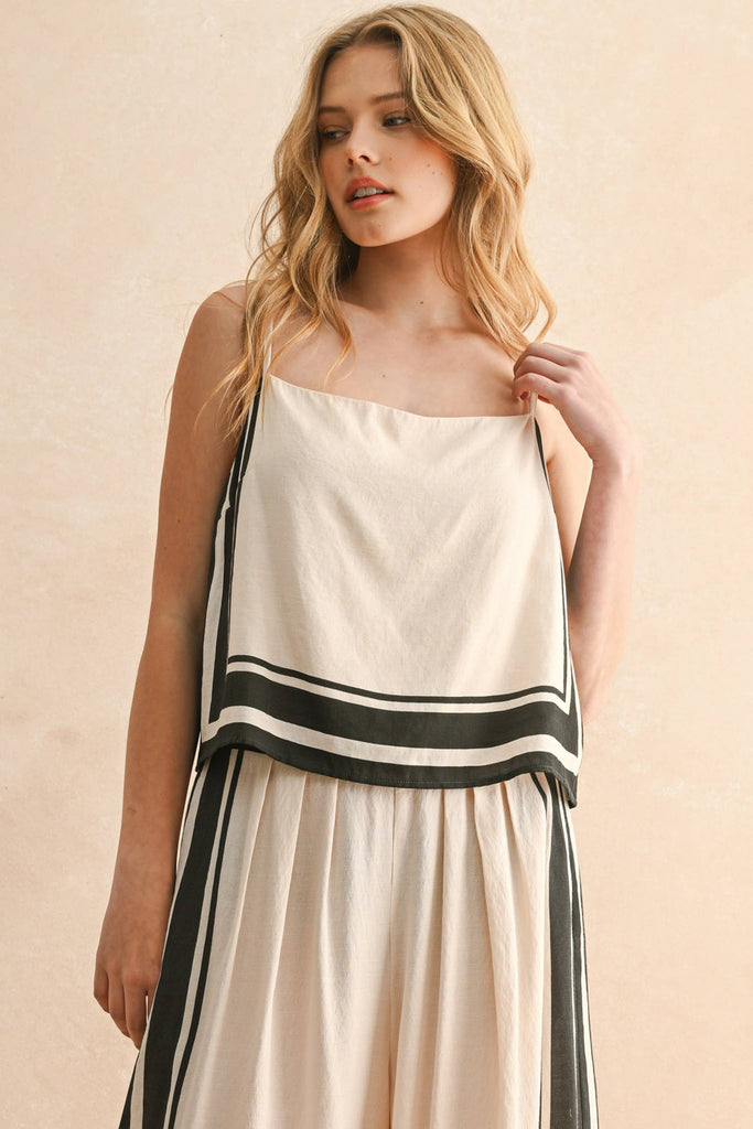 Woman wearing a cream and black striped two-piece set with a flowy top and wide-leg pants.