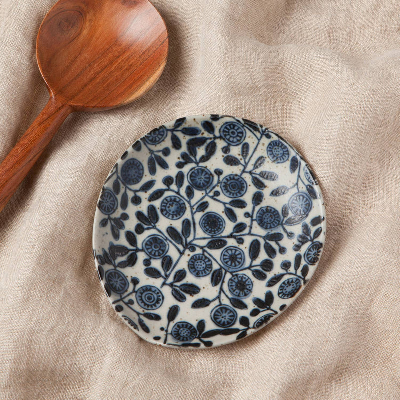 Ceramic plate with blue floral pattern on a beige fabric background