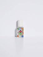 Maison Matine Nature Insolente perfume bottle with colorful leaf and beetle illustrations, placed on a vibrant yellow fabric and surrounded by green foliage.