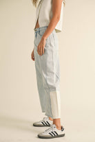 Model wearing light-wash wide-leg jeans with white contrast panels on the lower leg, styled with sneakers.