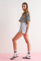 Close-up of a woman wearing gray elastic waist shorts with side zipper details.