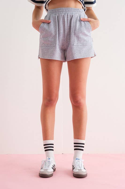 Close-up of a woman wearing gray elastic waist shorts with side zipper details.