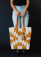 Large mustard and ivory woven tote bag with geometric pattern, leather handles, and a tassel accent