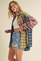 Woman wearing an oversized plaid colorblock flannel shirt in pink, yellow, and navy tones with raw hems.