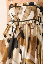 Woman wearing an abstract printed romper in warm earth tones with a smocked bodice and flowy shorts.
