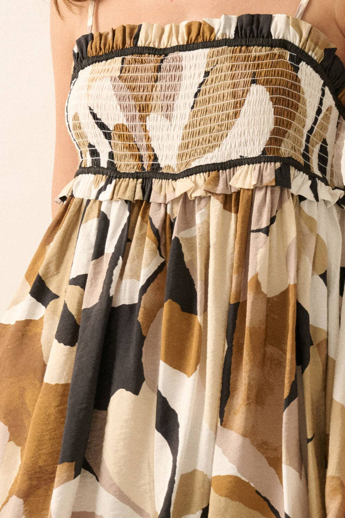 Woman wearing an abstract printed romper in warm earth tones with a smocked bodice and flowy shorts.