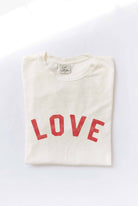 Ivory "LOVE" graphic t-shirt with bold red vintage-style lettering, made from soft cotton for a relaxed and comfortable fit.