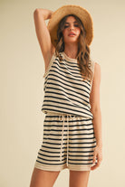 Woman wearing a sleeveless knit romper with black and cream stripes and a drawstring waist.